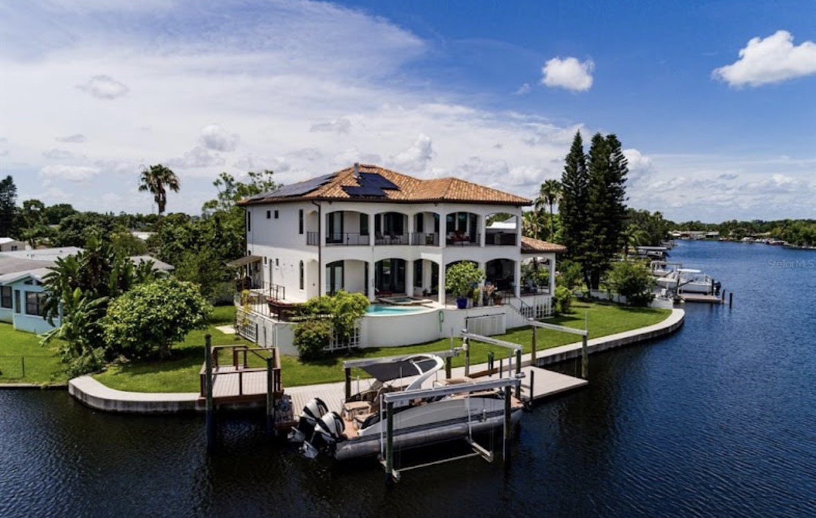 Aerial view of a completed waterfront Mediterranean custom home with a private dock