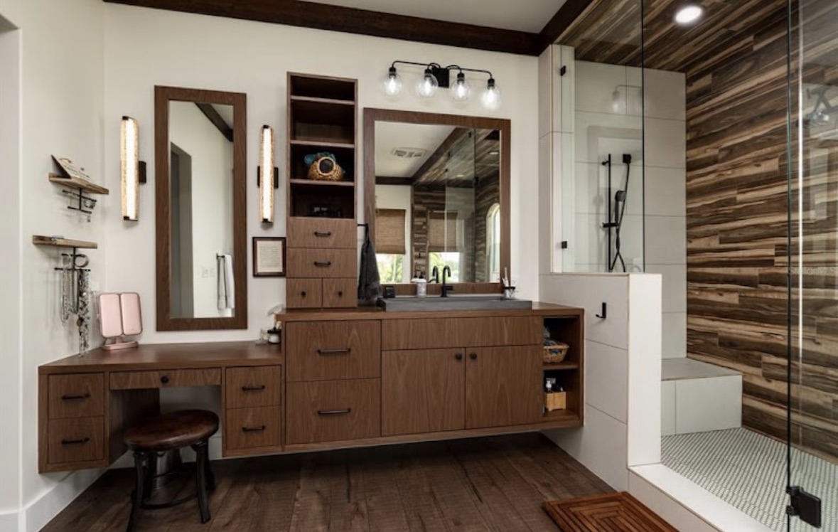 Custom floating vanity with warm wood drawers and a walk-in shower
